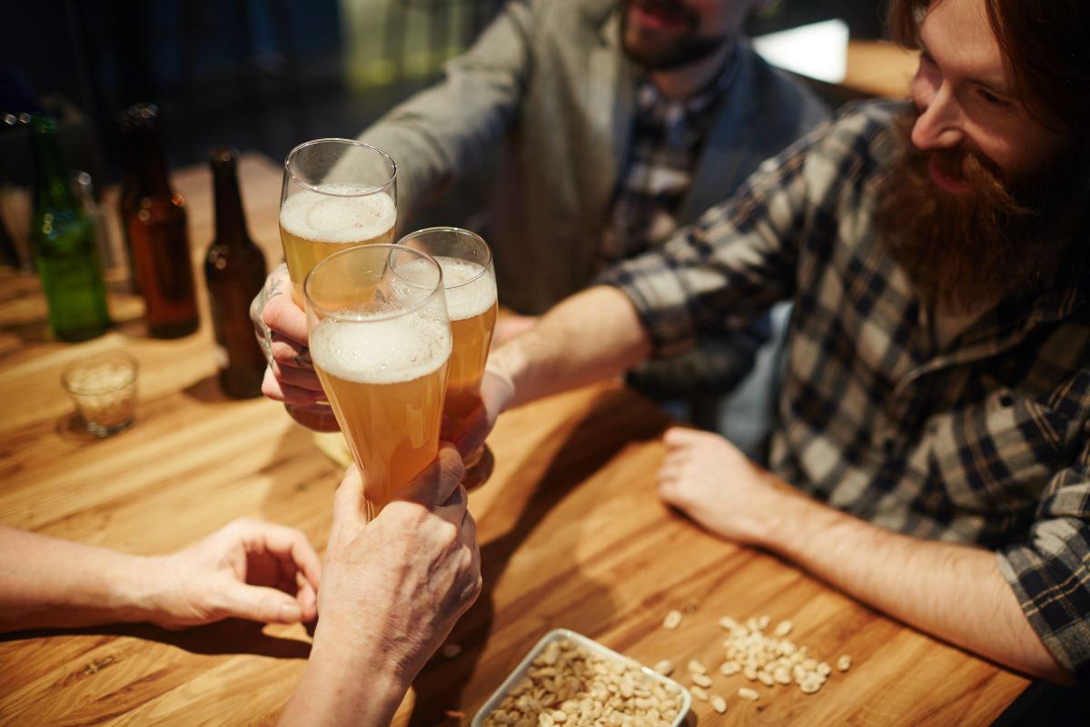 men toasting at a bar with beer - best happy hour NYC