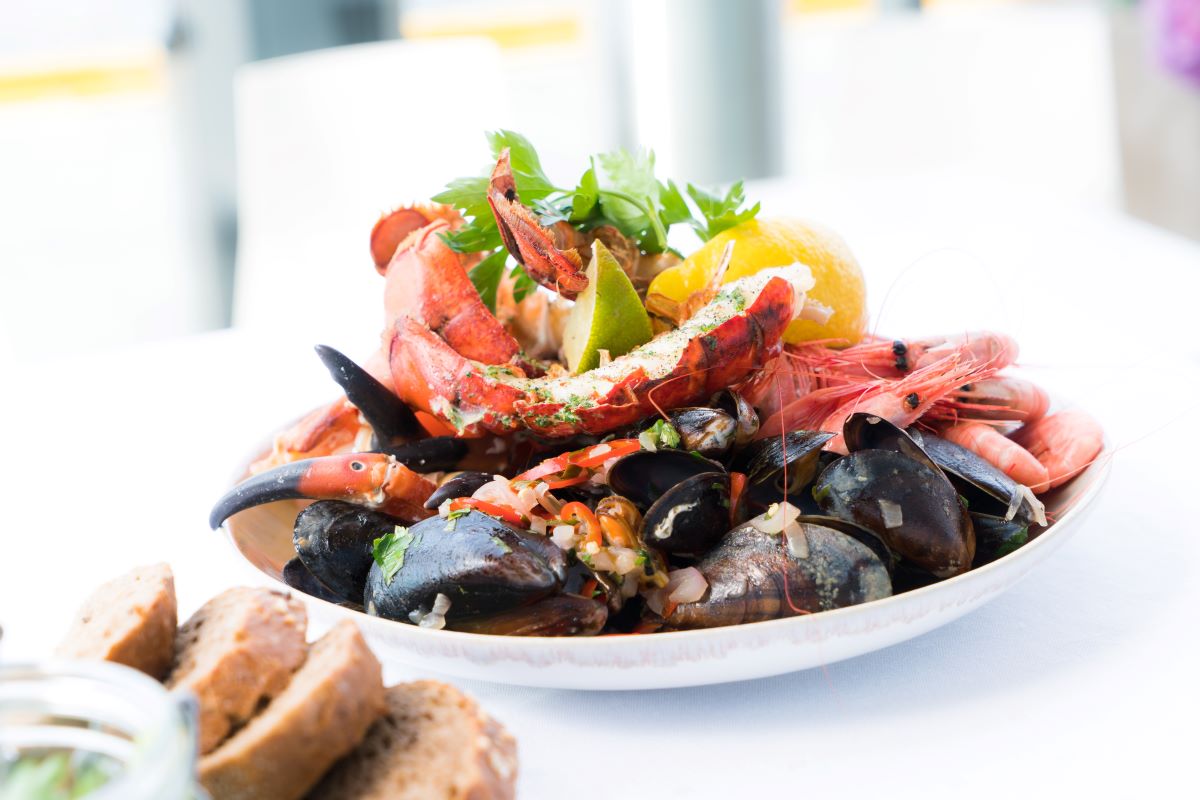 white plate of mussels and crab on white table cloth and bread 