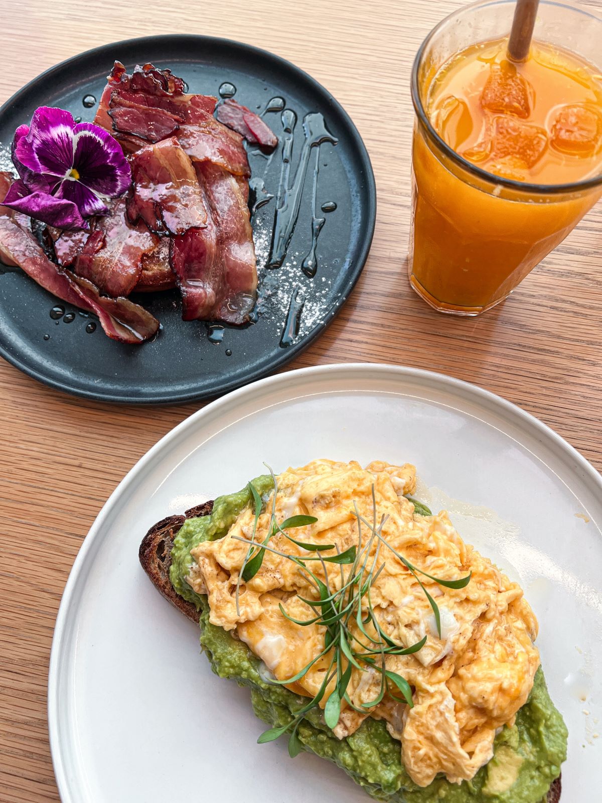 toast with avocado and scrambled eggs, bacon and orange juice