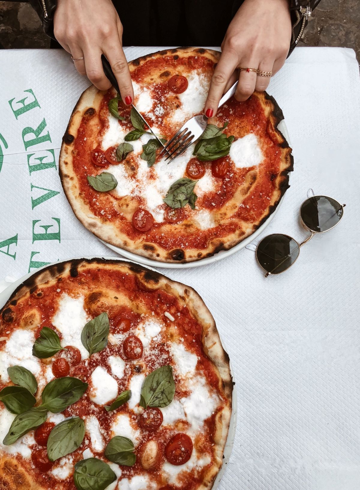 woman cutting into pizzas