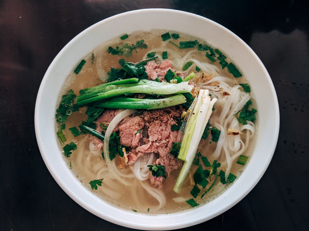 Overhead shot of beef pho garnished with chives in a white bowl