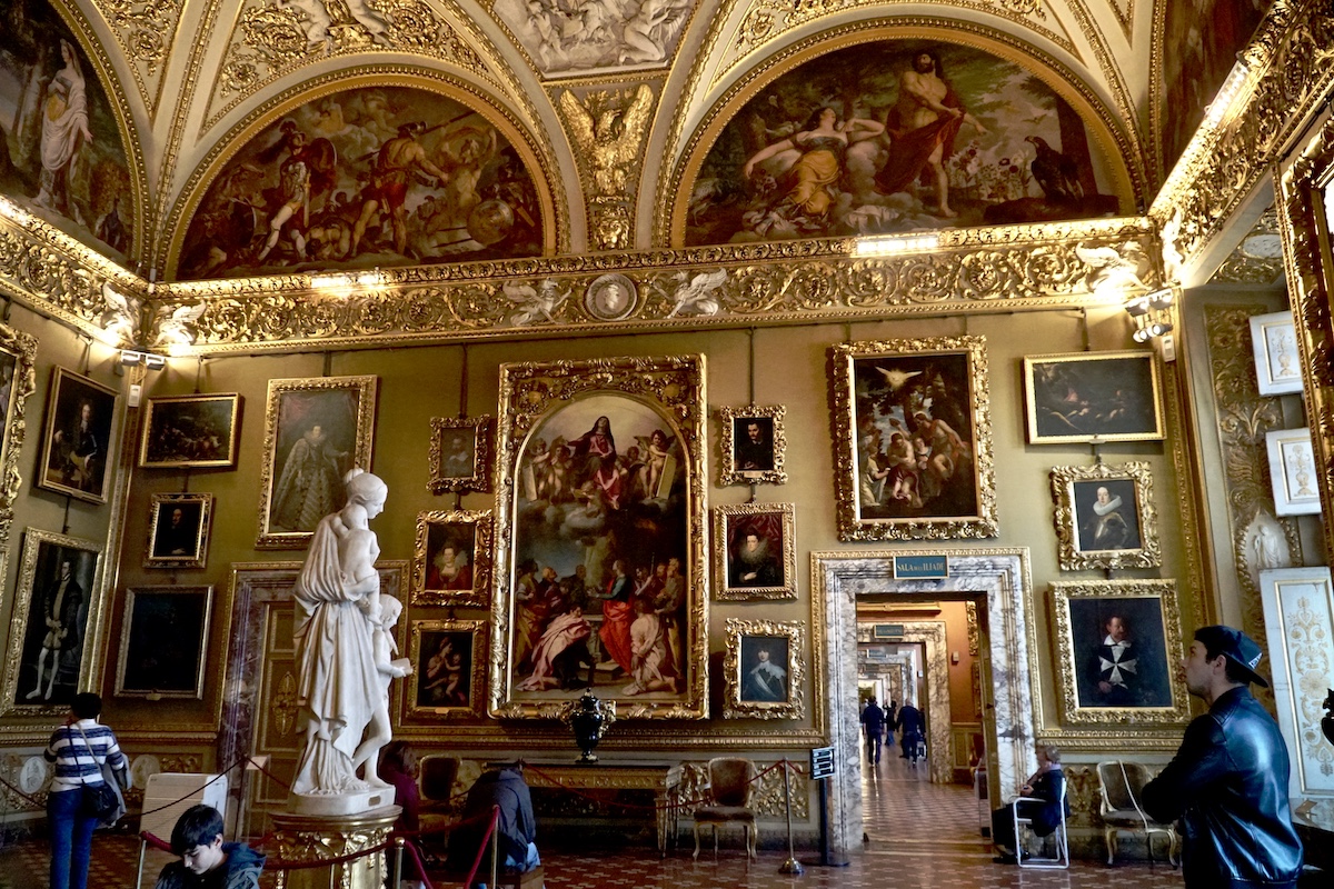 Large art gallery with ornate gold detailing and a marble sculpture of a woman in the foreground