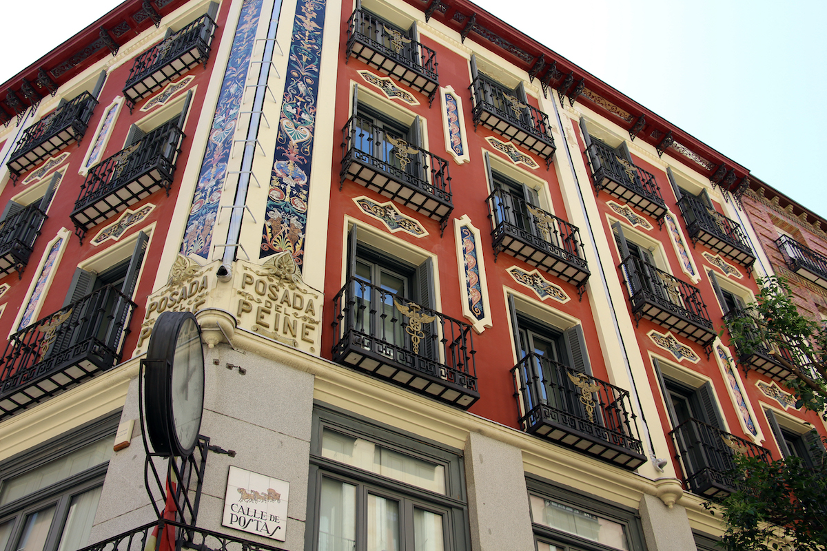 Exterior of a red hotel building with wrought iron balconies and colorful tile detailing