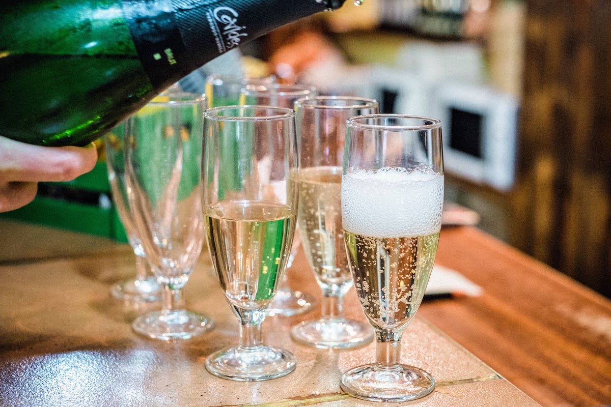 Cava being poured from a bottle into several glasses