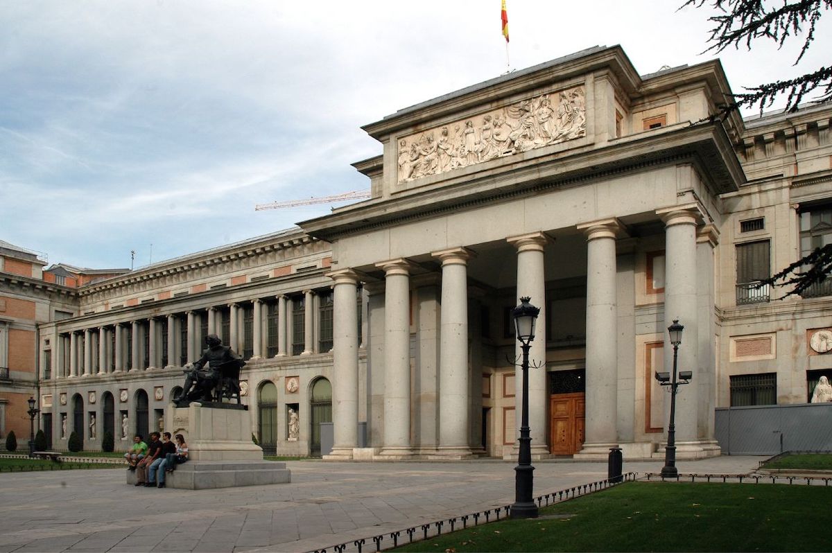 Exterior of the Prado Museum in Madrid decorated with columns, with a statue out in front