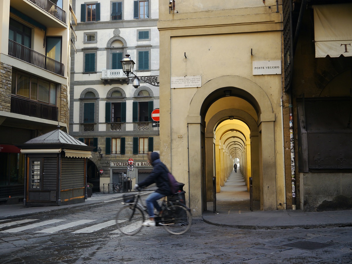 A man rides his bike by the Ponte Vecchio in the early morning in Florence