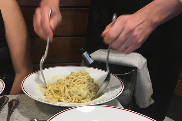 Pasta with cacio e pepe being mixed at the table at one of the restaurants in Vatican City.