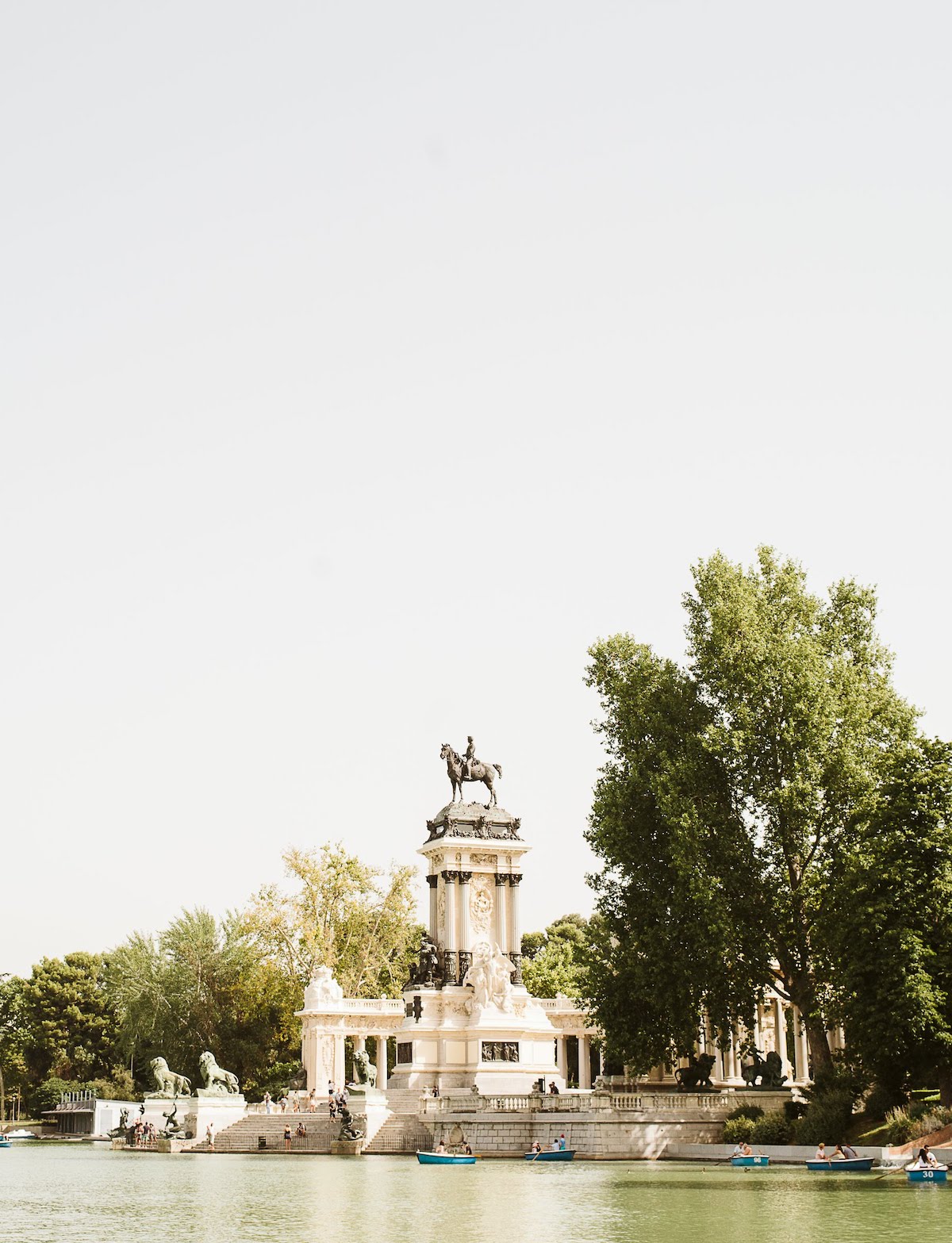 Boats in a small lake in front of a large statue monument.