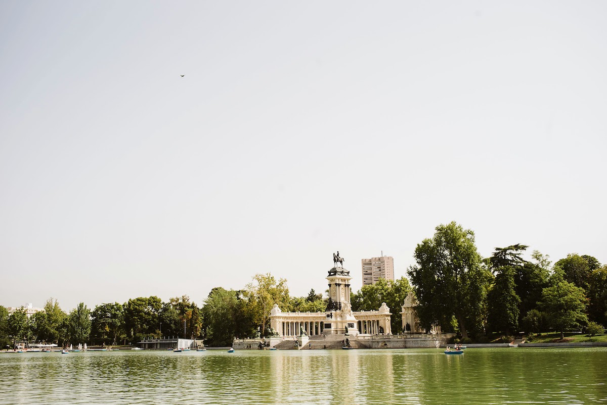 The lake at Retiro Park in Madrid with a monumental statue in the background.