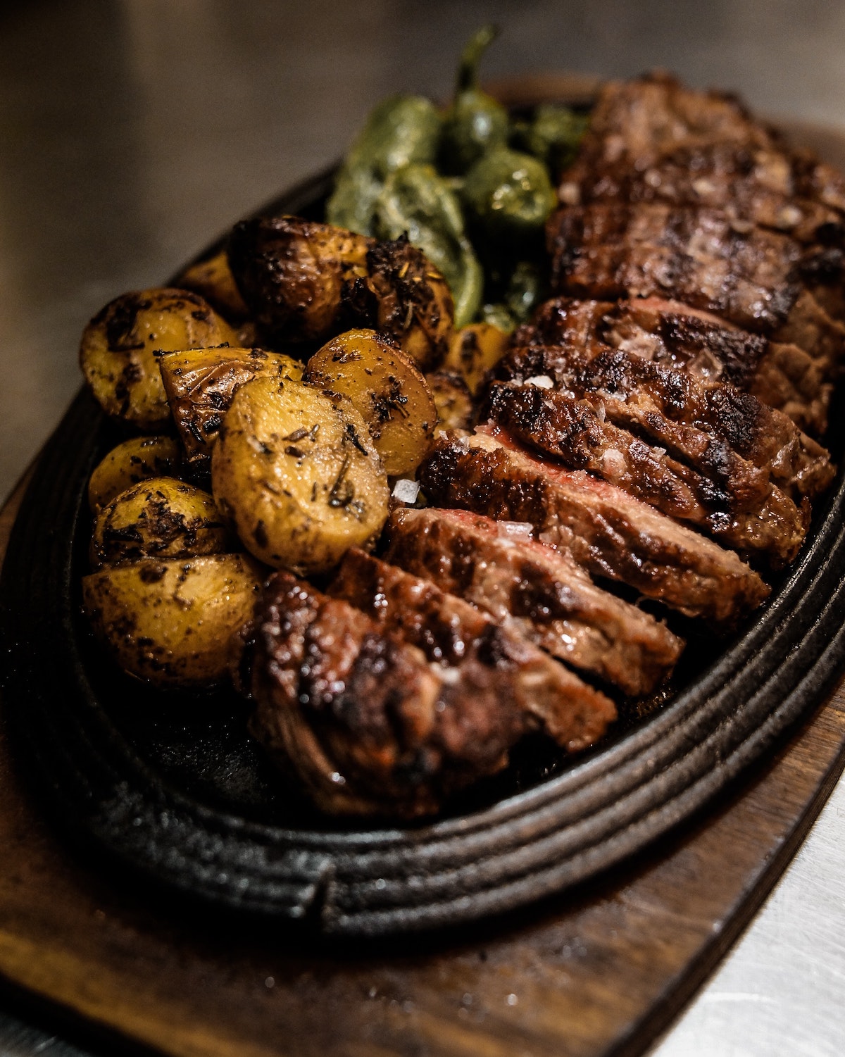 Roasted lamb with potatoes and green peppers served on a black plate