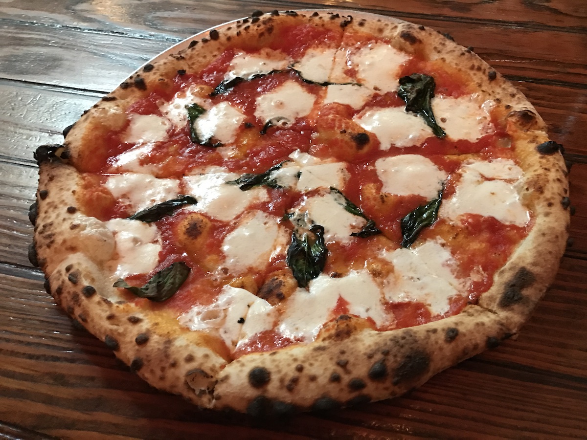 Whole Neapolitan style pizza with mozzarella cheese and basil