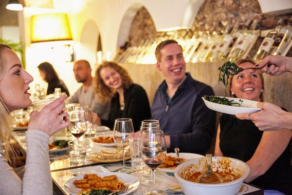 Group of people sharing a meal with pasta and wine in Rome