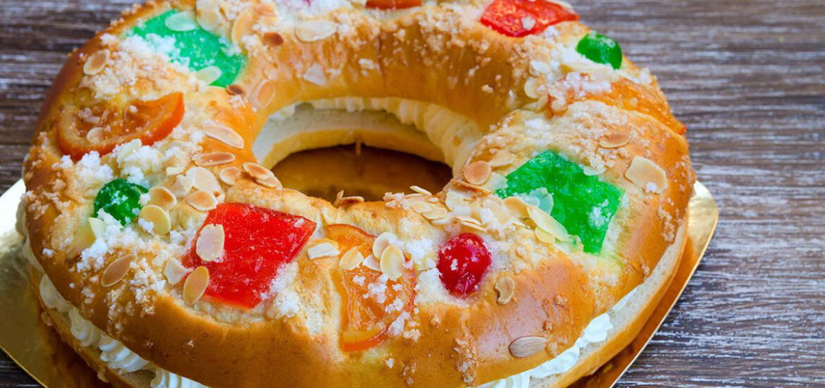 Large donut-shaped cake filled with whipped cream and decorated with red and green candied fruit.
