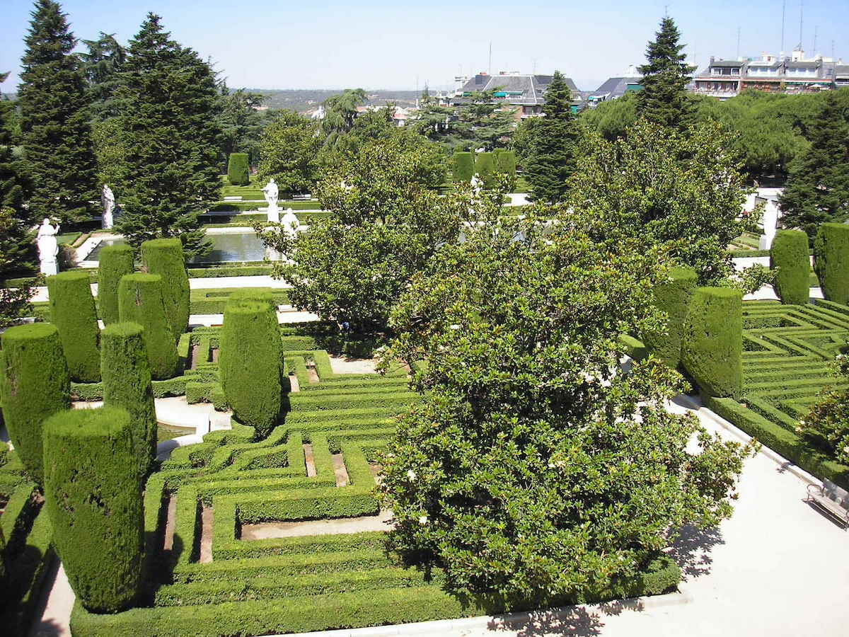 Green gardens with hedges and trees cut into neat geometrical shapes.