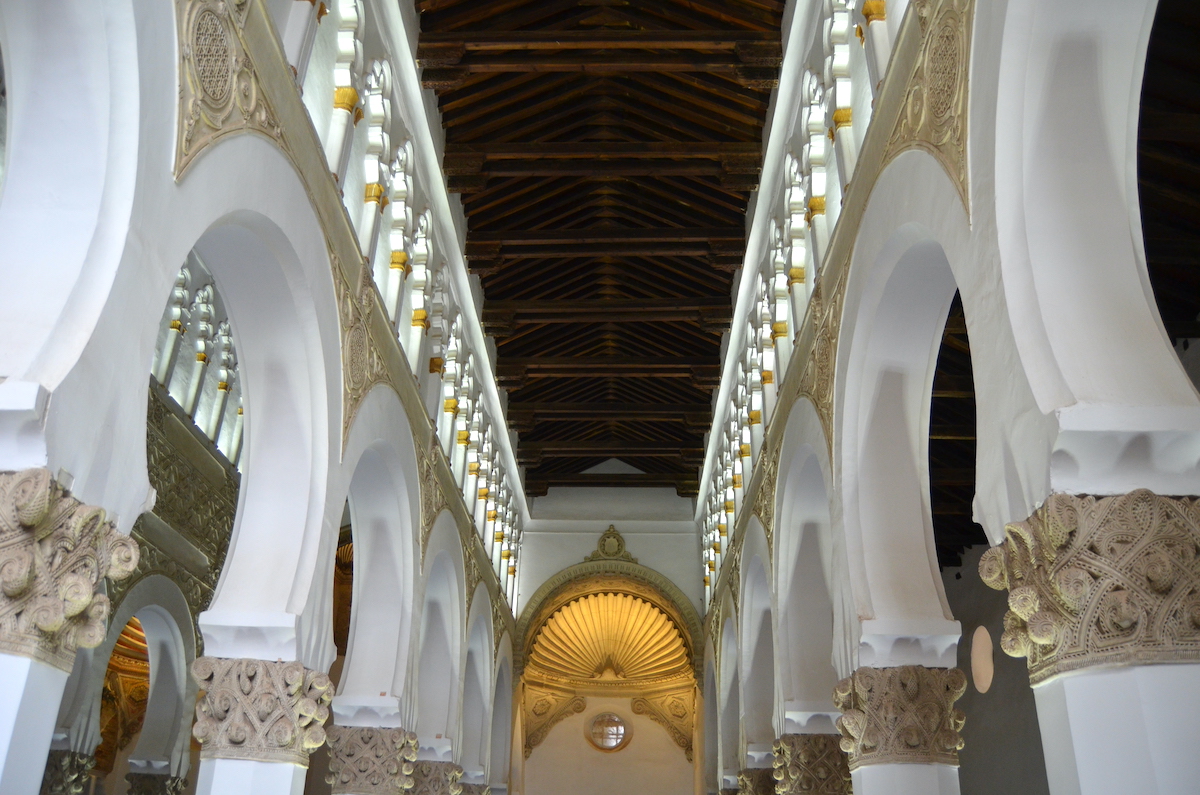 Interior of a synagogue decorated with white arches.