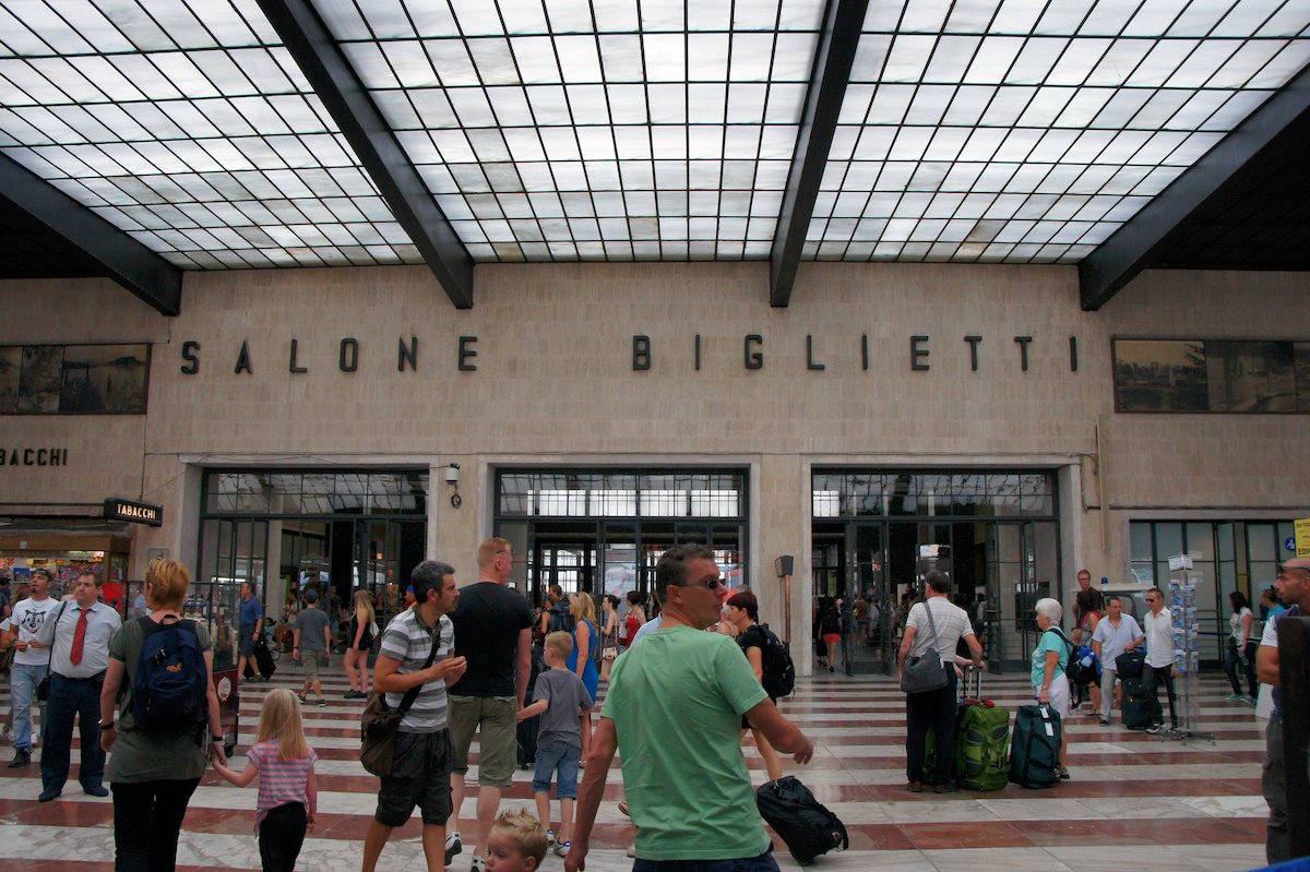 Interior of a crowded train station in Florence, Italy with a man in a green shirt in the foreground