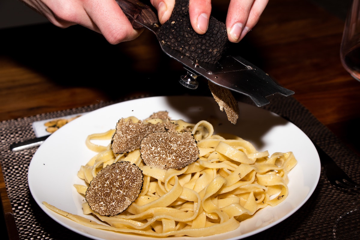 Truffles being gently shaved over the top of fettuccine pasta