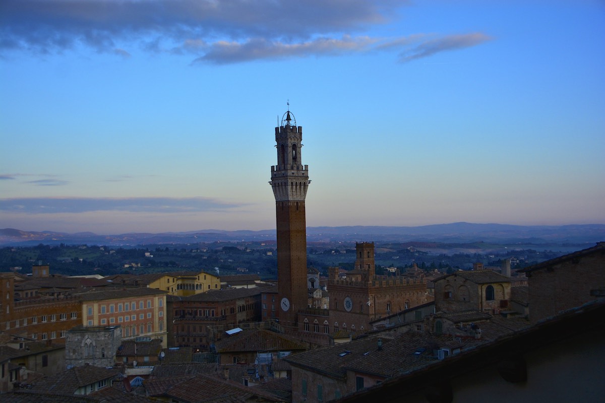 Tall brick tower over Siena, Italy at dusk