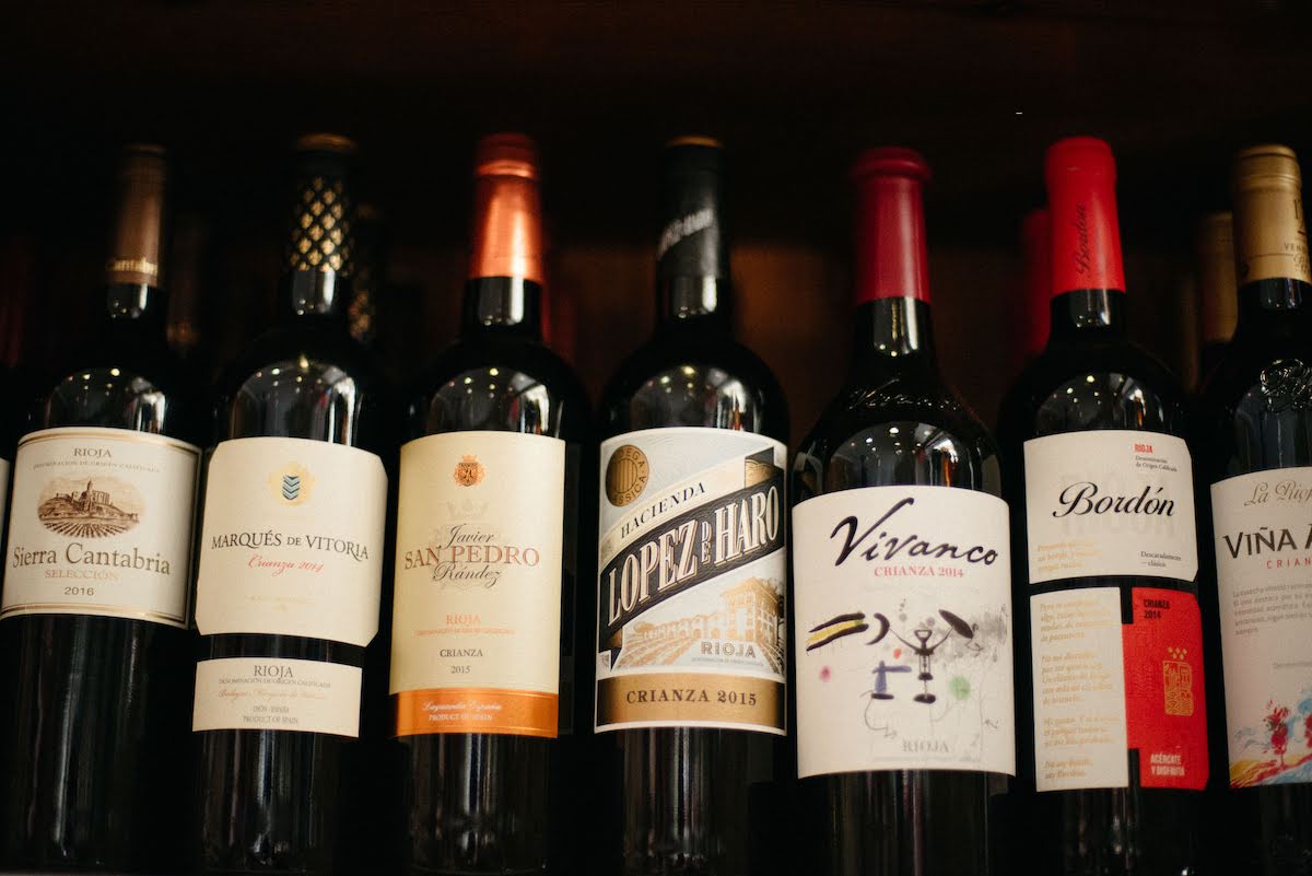 Seven Spanish wine bottles lined up on a shelf.