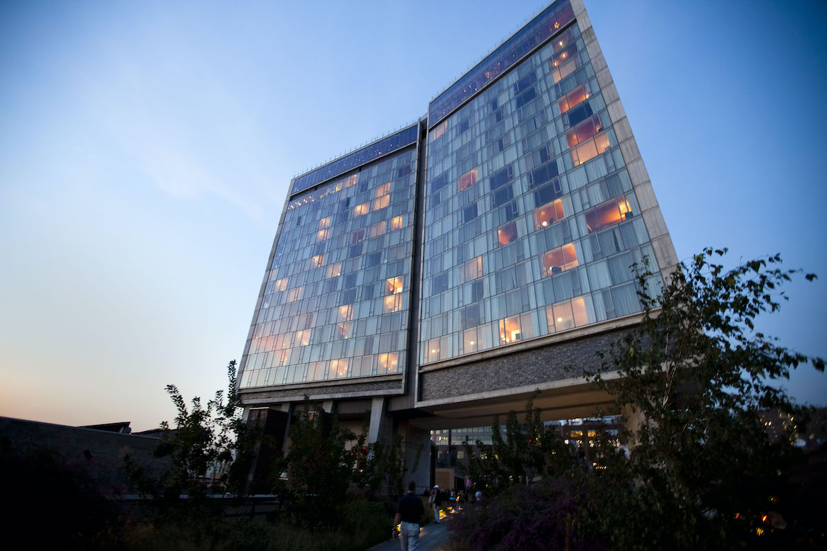 Modern, multi-story hotel with large windows revealing some room with lights on