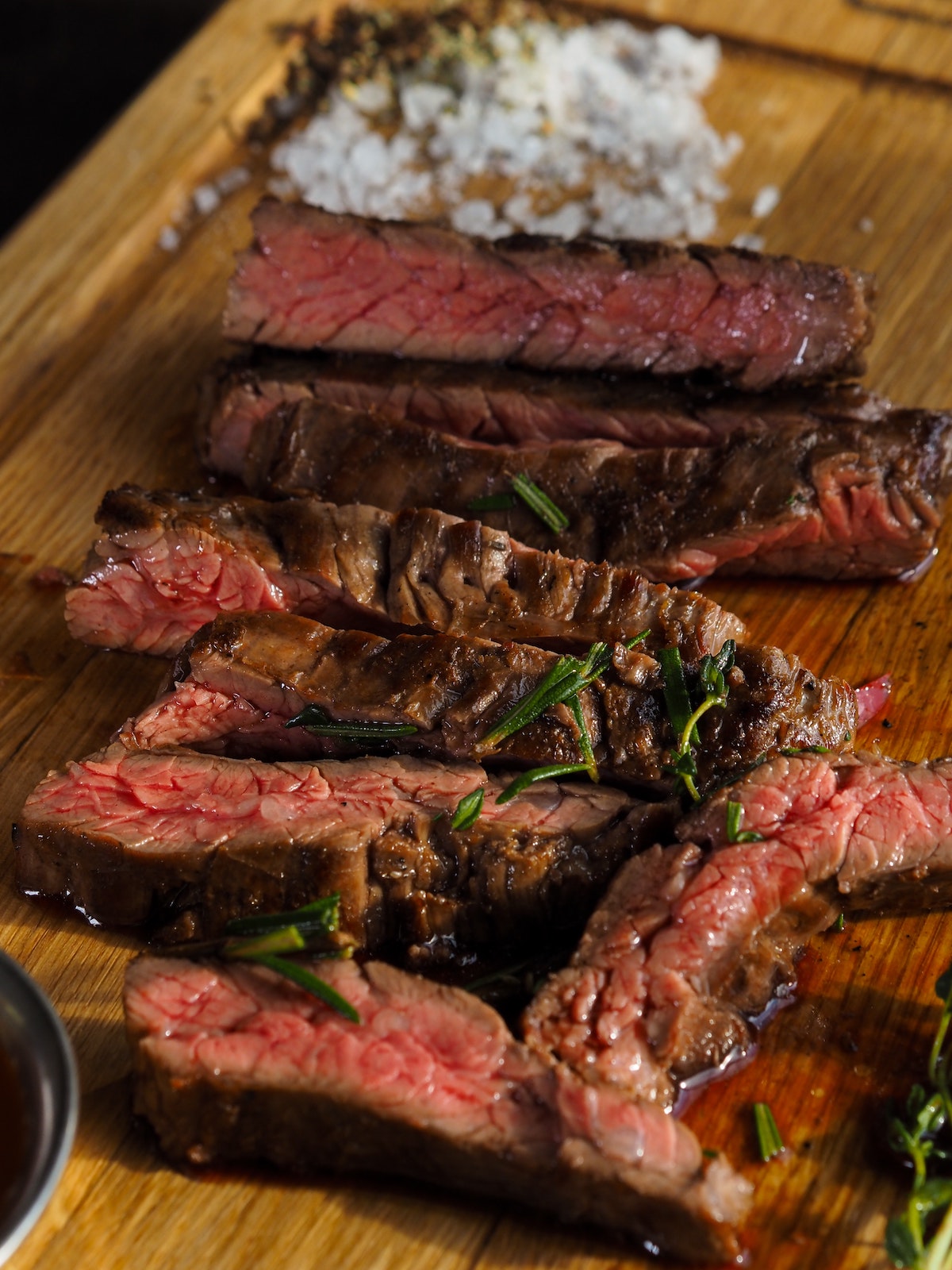Rare steak garnished with herbs on a wooden board