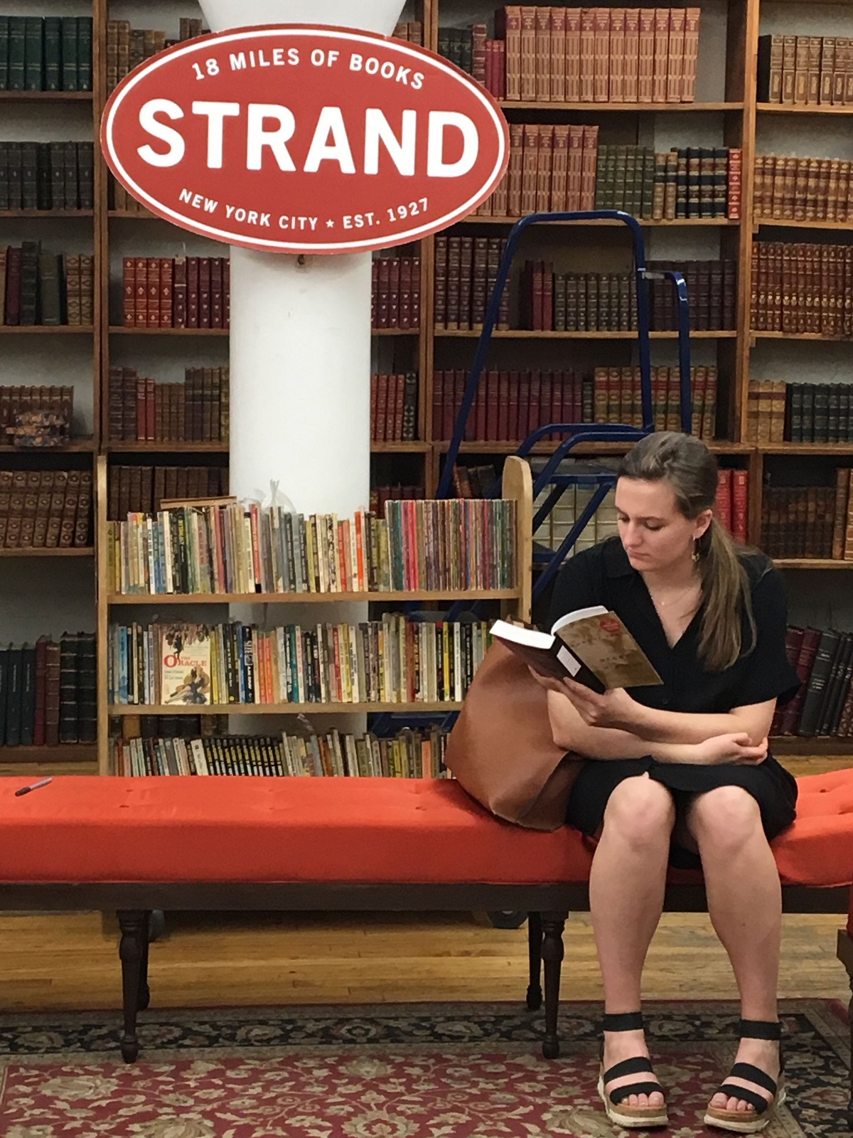 Woman reading a book on a red sofa at a bookstore