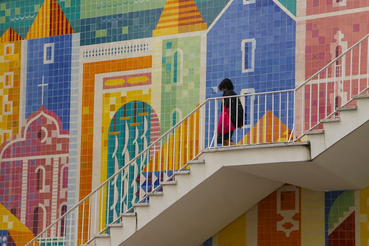 tiled photo of buildings as a woman walks down stairs in the foreground. 