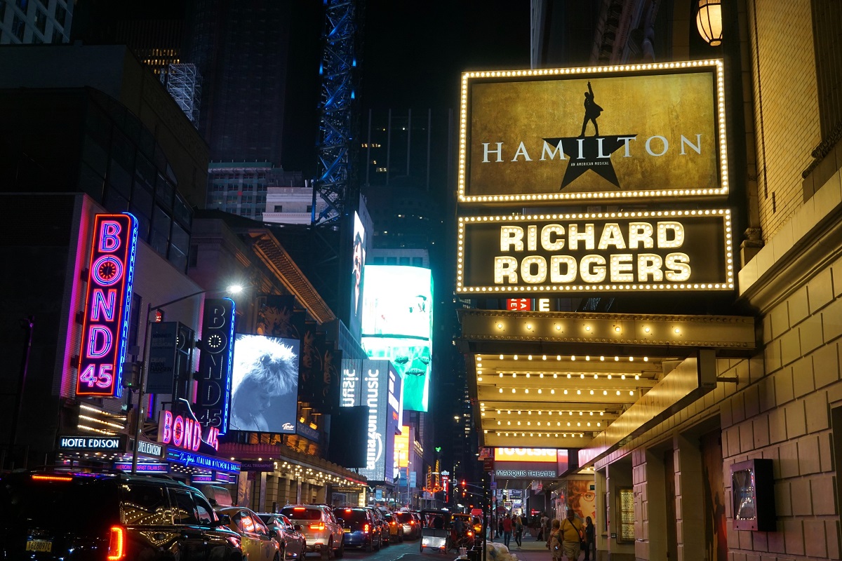 Outdoor street scene at night with neon lights advertising theater shows