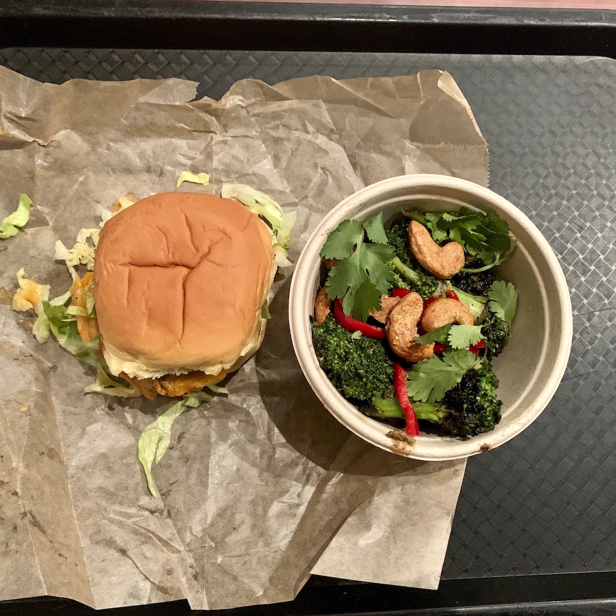 Overhead shot of a vegetarian hamburger on paper wrapping and a small salad in a bowl