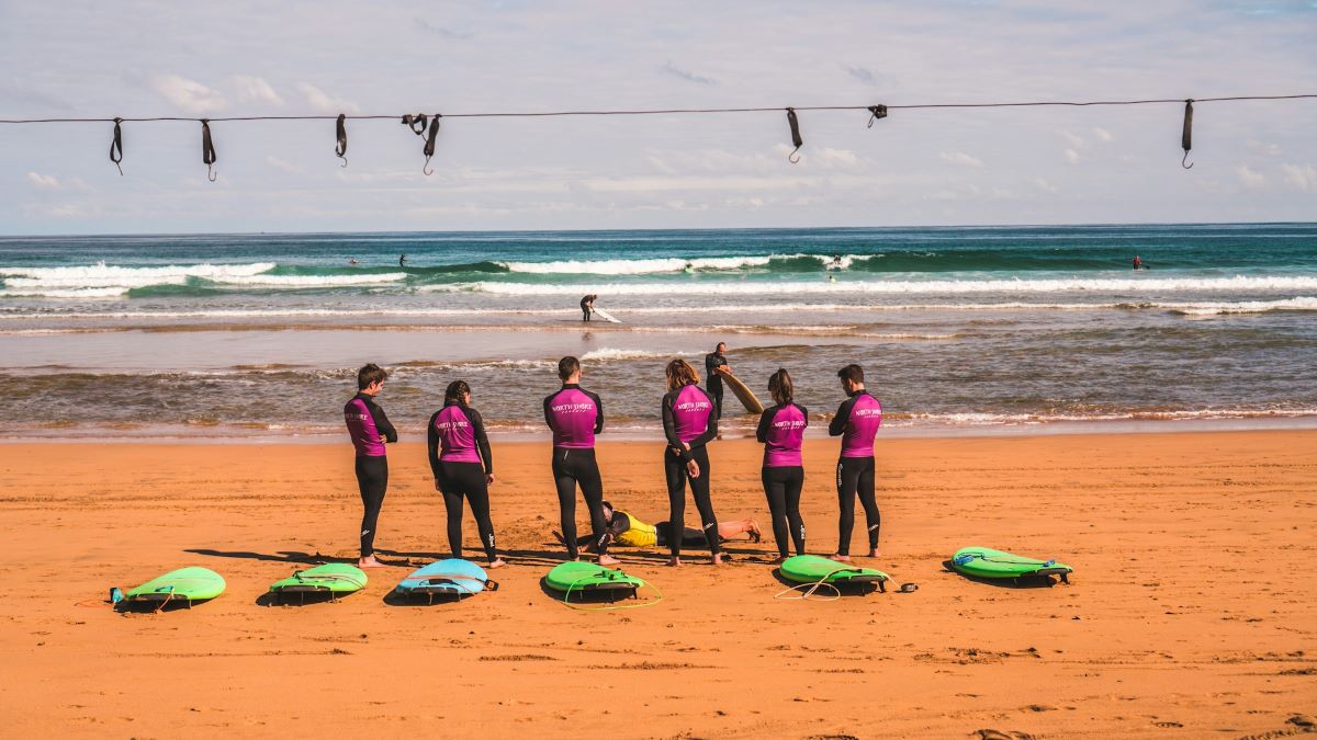students on beach talking surfing lessons in San Sebastian
