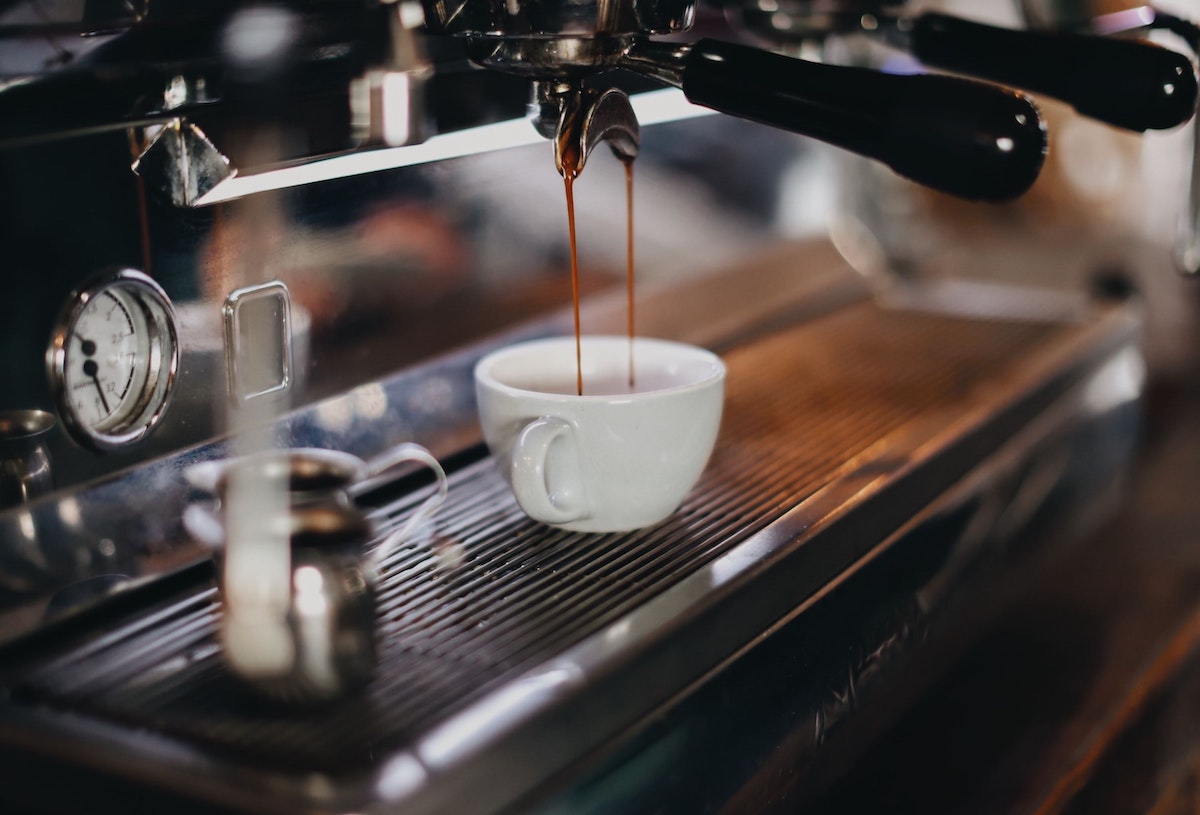 close up of an espresso machine dripping espresso into a small white cup