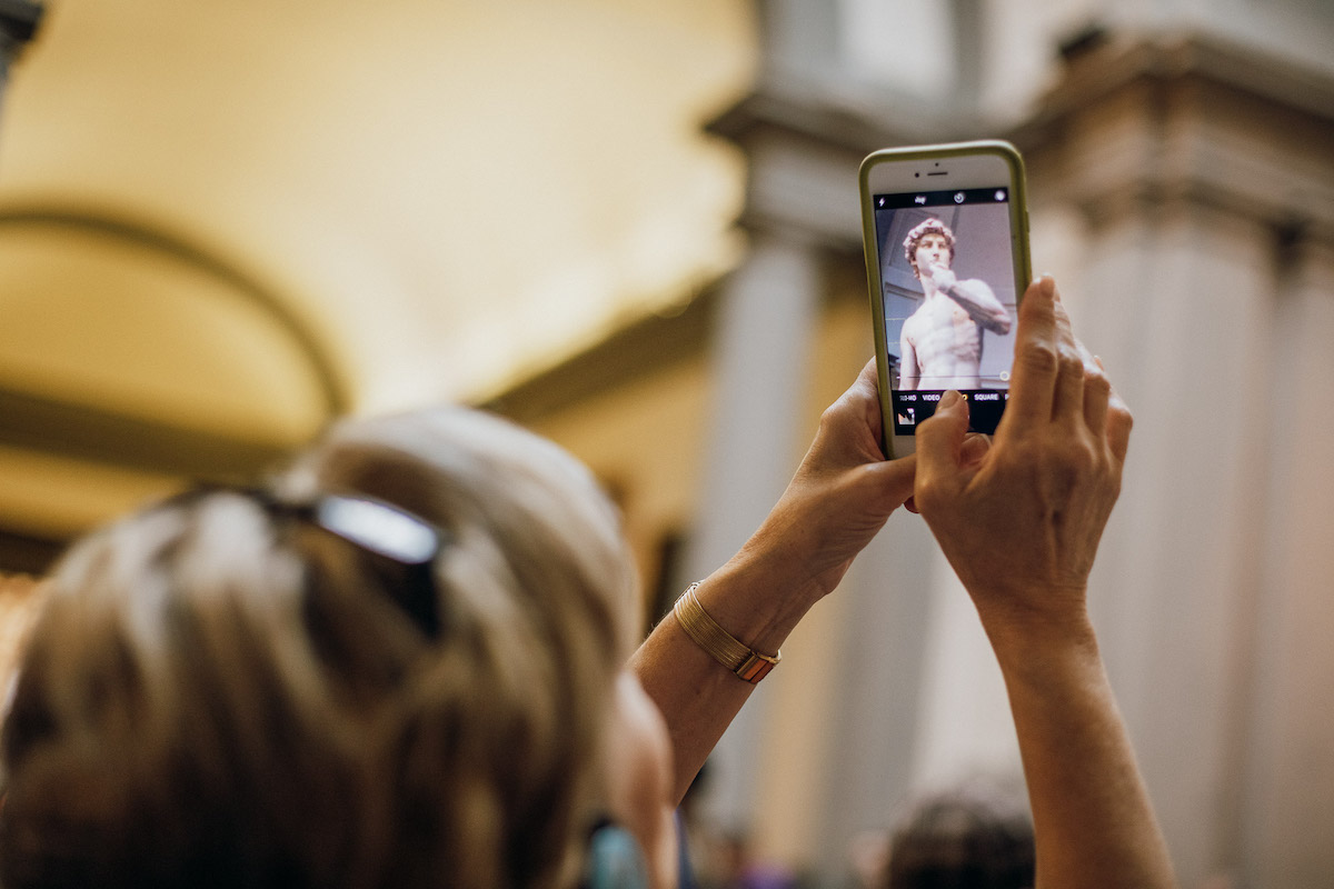 Close up of a woman taking a photo of Michelangelo's David statue on an iPhone
