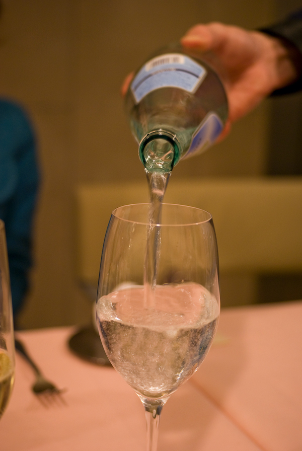 Pouring a bottle of sparkling water into a glass
