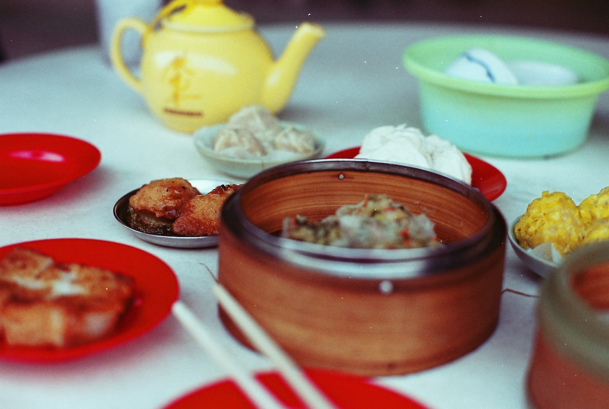 Close up of a table set with a yellow teapot and several plates of dim sum