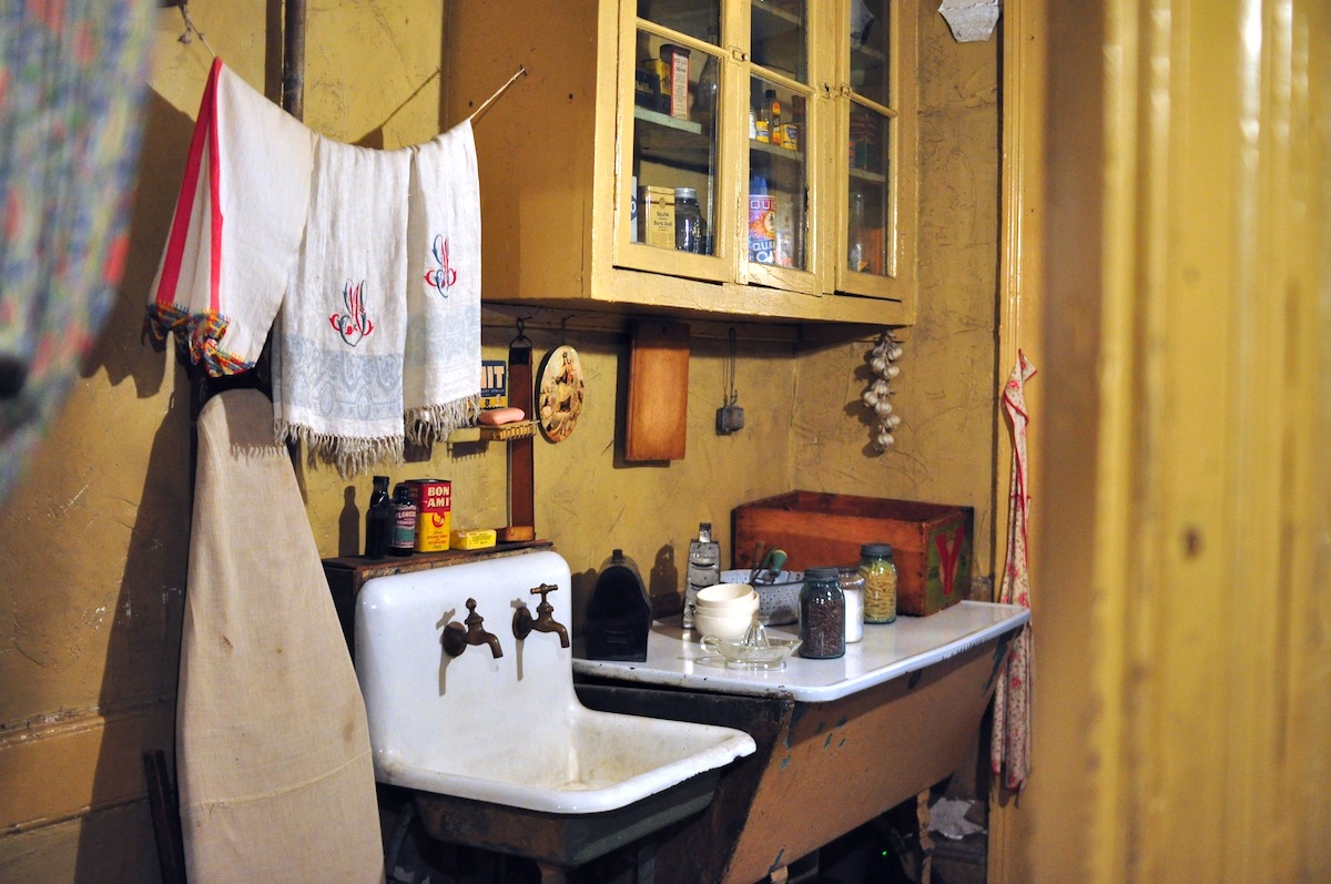 Old-fashioned kitchen in a tenement apartment with towels hanging above a small sink