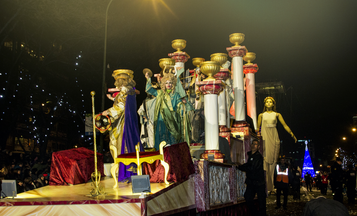 Parade float with people dressed as kings and queens standing among gilded columns.