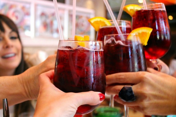 Friends clink their glasses of Spain's popular red wine spritzer, stirred with lemon soda and topped with an orange slice. Try our favorite Spanish drinks on one of our food tours!