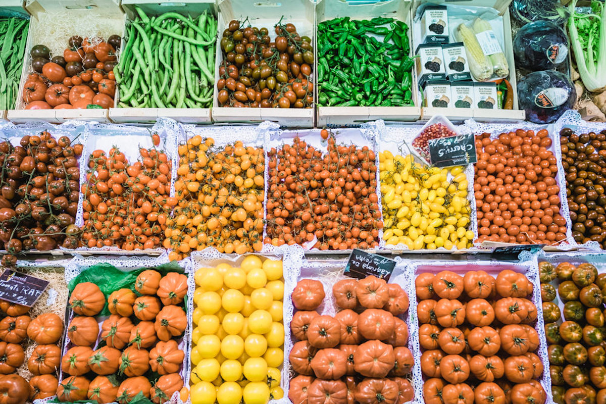 Stalls of yellow and red tomatoes at a market.