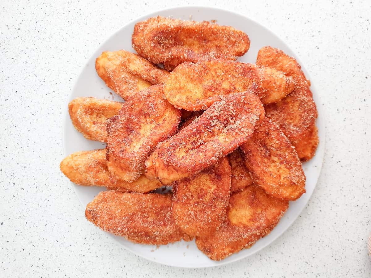 Plate piled with small pieces of fried bread dusted with cinnamon sugar