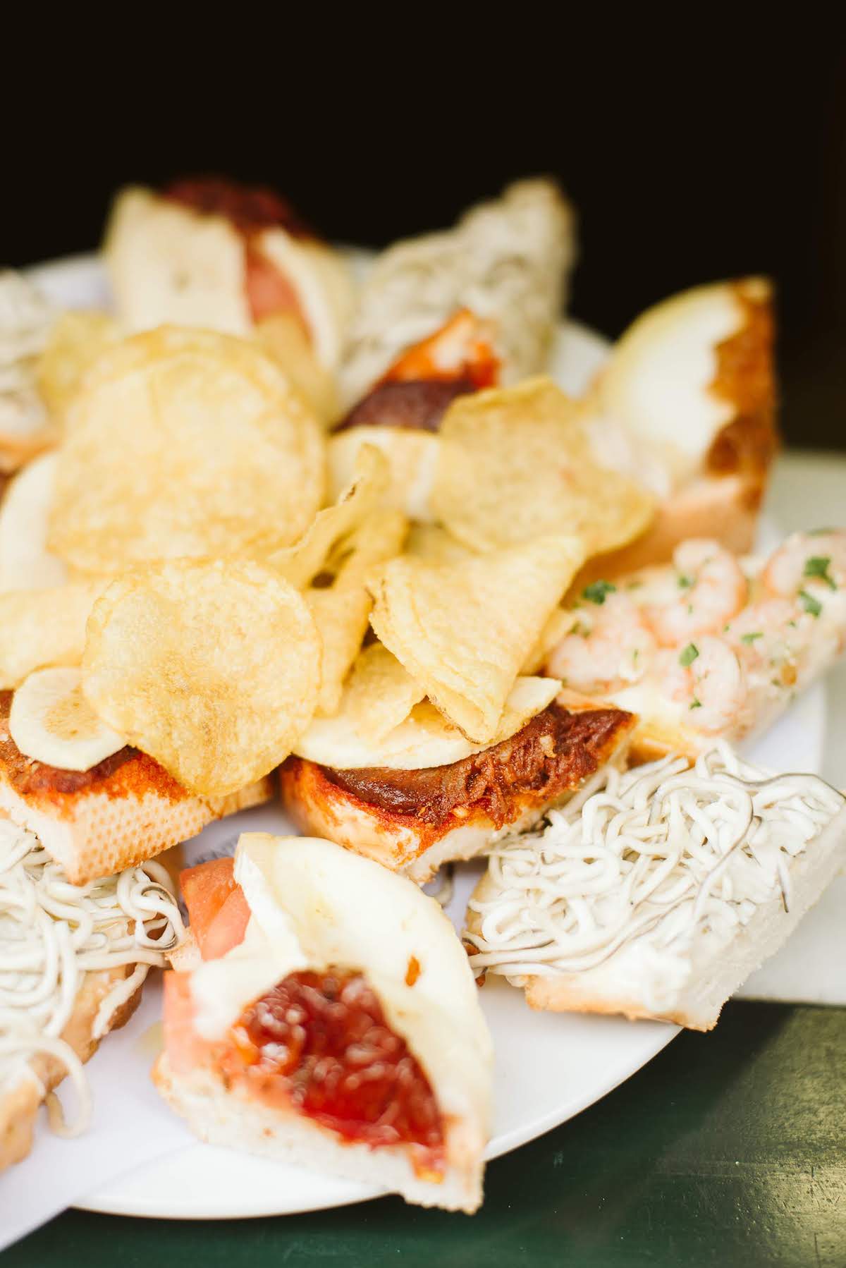 Plate of small open faced sandwiches with various toppings, with a pile of potato chips in the middle.