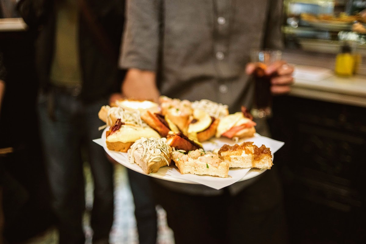 Person holding a tray full of various open-faced sandwiches.