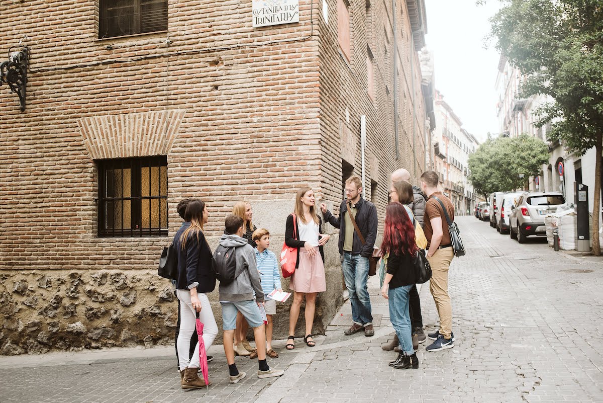 A tour group listening to a guide speak in front of an old brick building.
