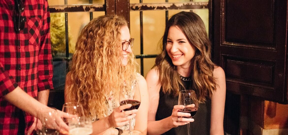 Two women smiling and drinking red wine.