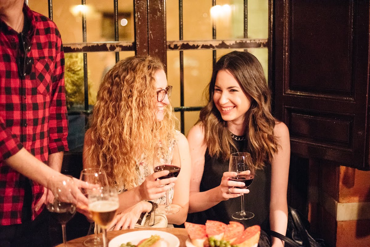 Two women smiling and drinking red wine.