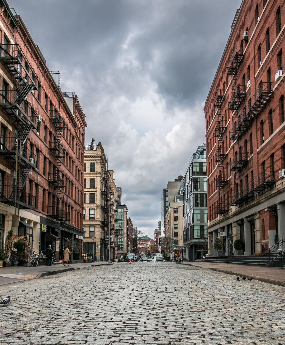 Cobblestone street lined by multi-story brick buildings on an overcast day