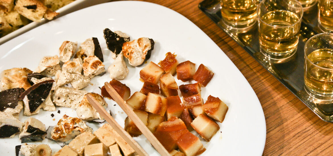 Pieces of Spanish Christmas candy on a white plate beside several small glasses of white wine