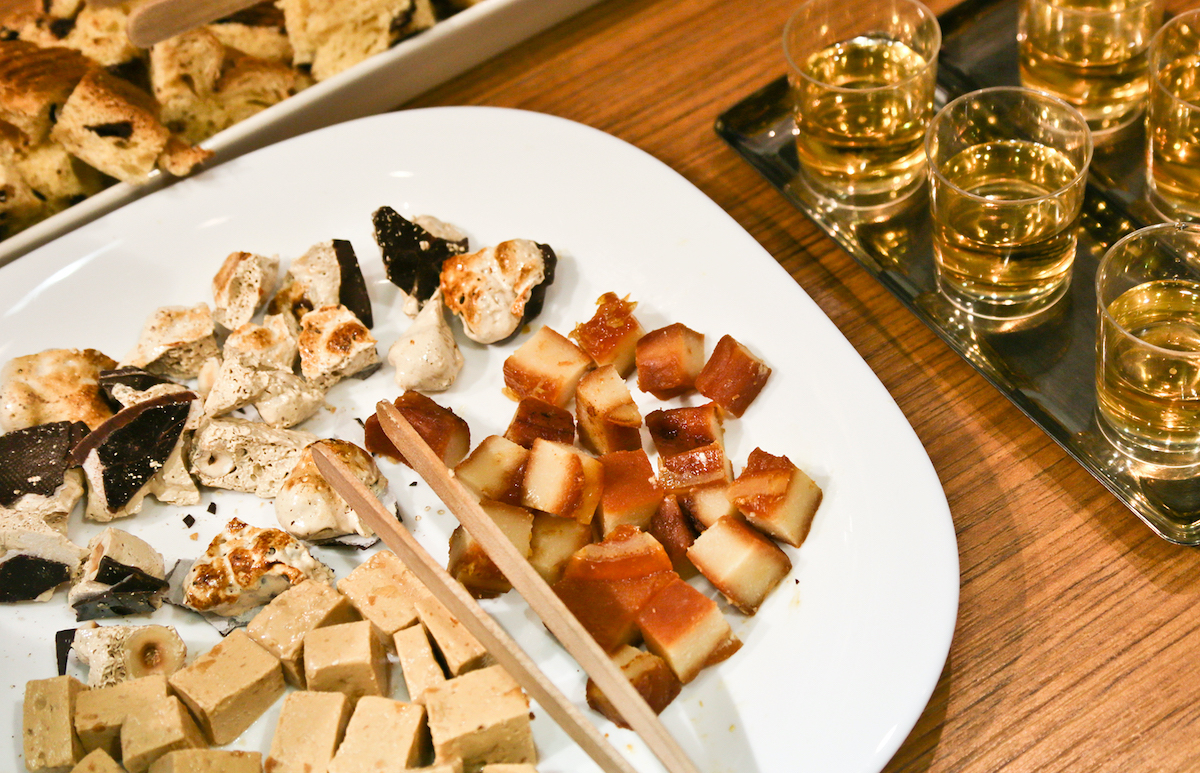 Pieces of Spanish Christmas candy on a white plate beside several small glasses of white wine