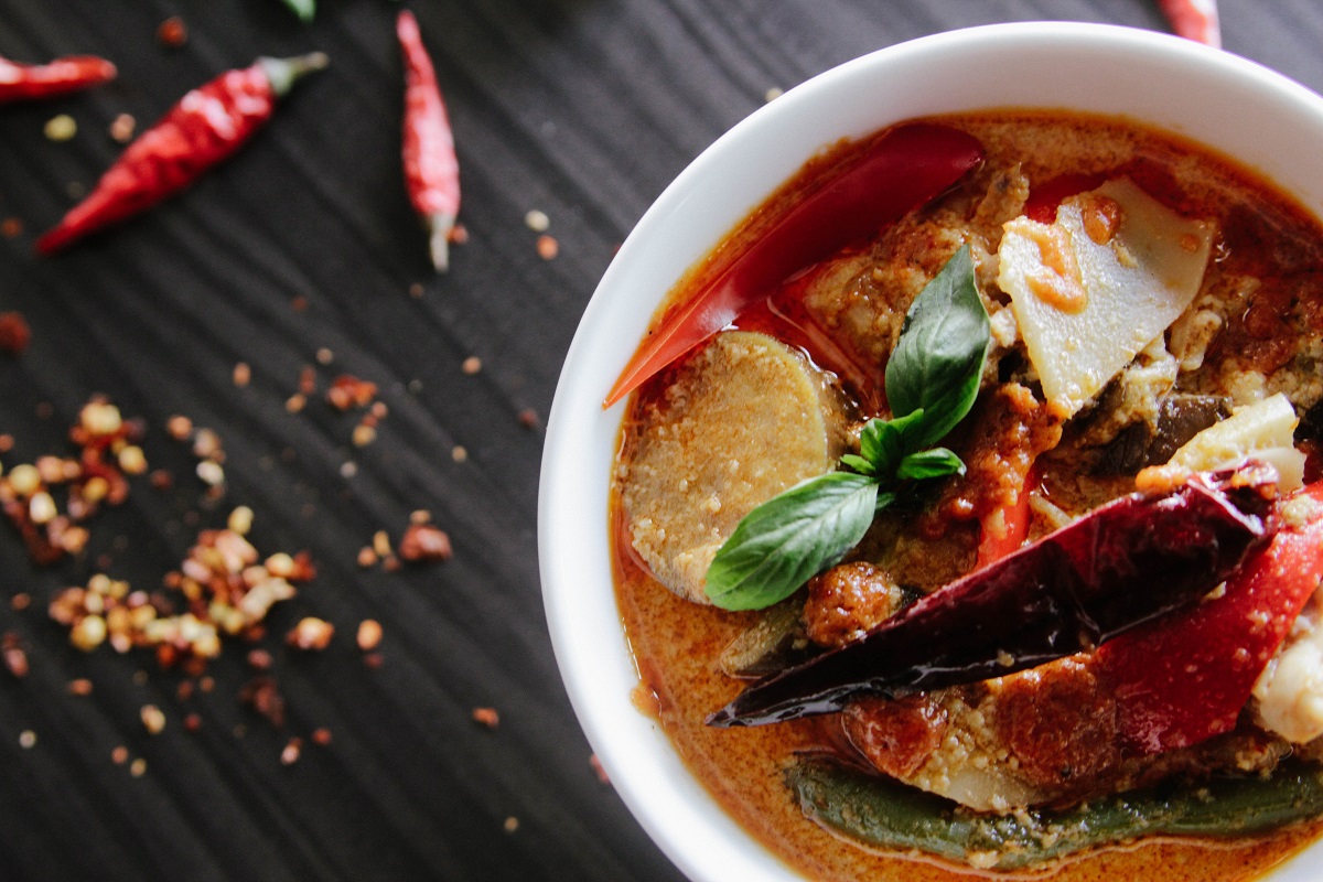Bowl of watery red curry with chilis and chili flakes