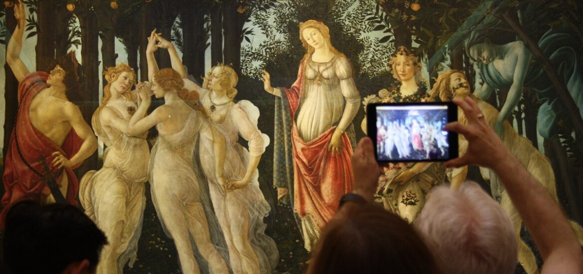 Visitors in an art museum take pictures of a painting of women in a forest