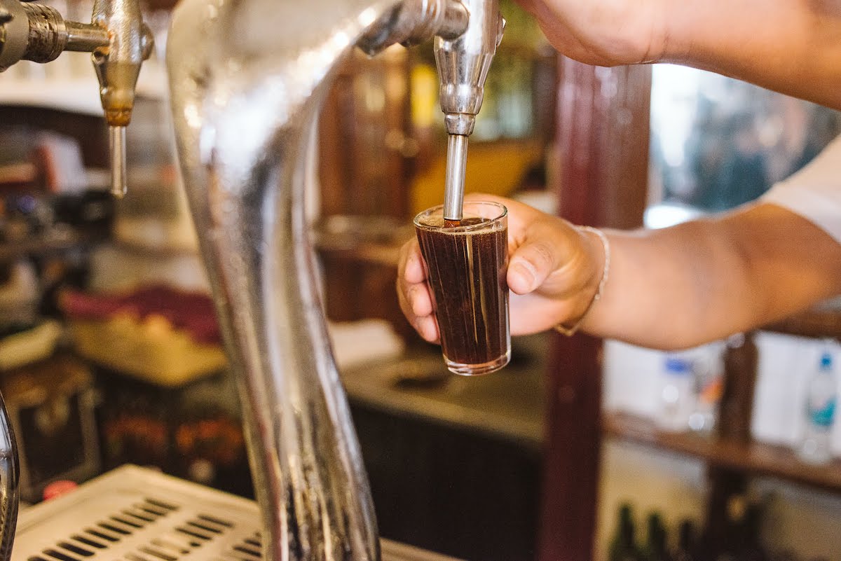 Close up of a bartender pouring vermouth on tap into a small glass